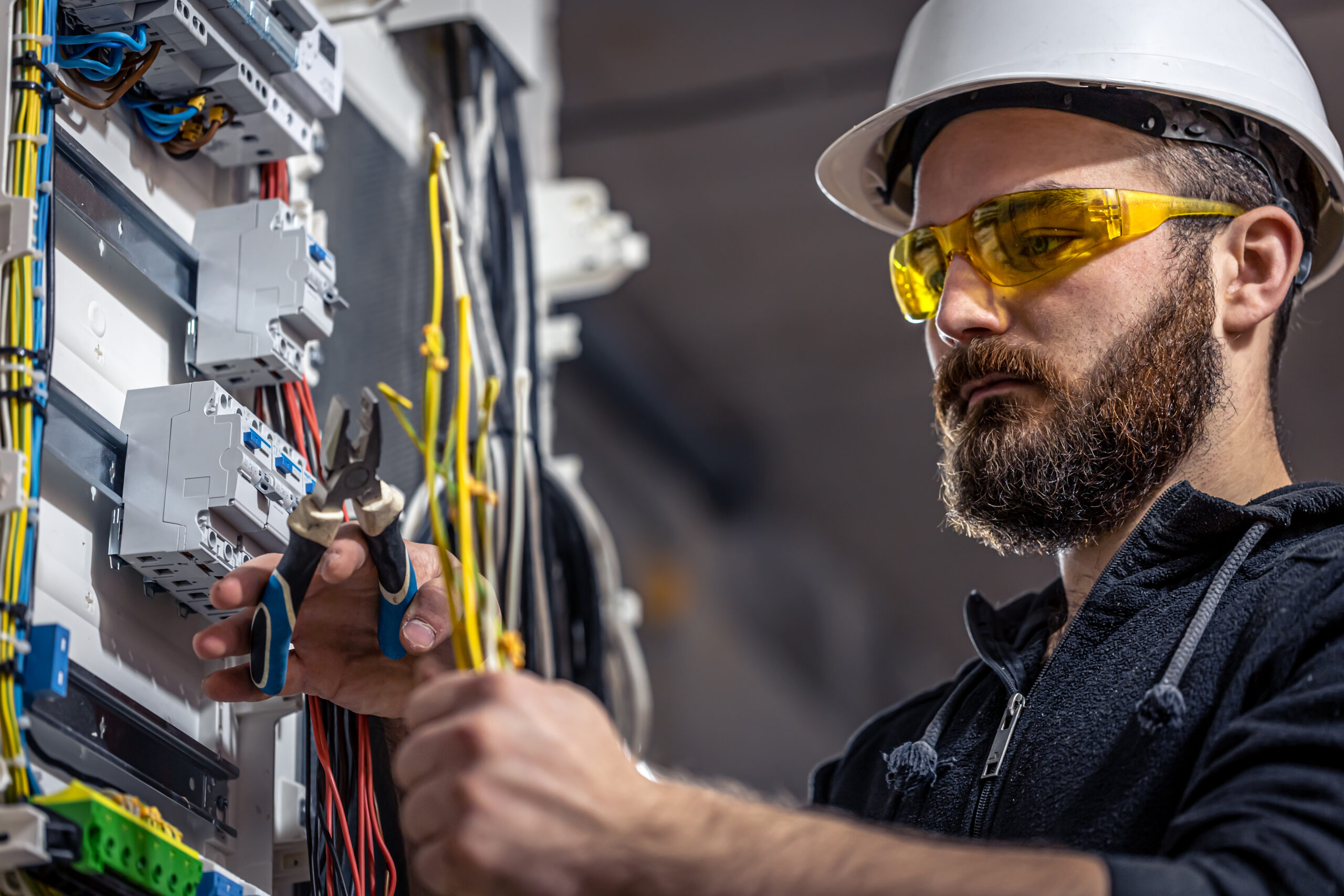 Elektricien met helm en veiligheidsbril werkt aan installatie