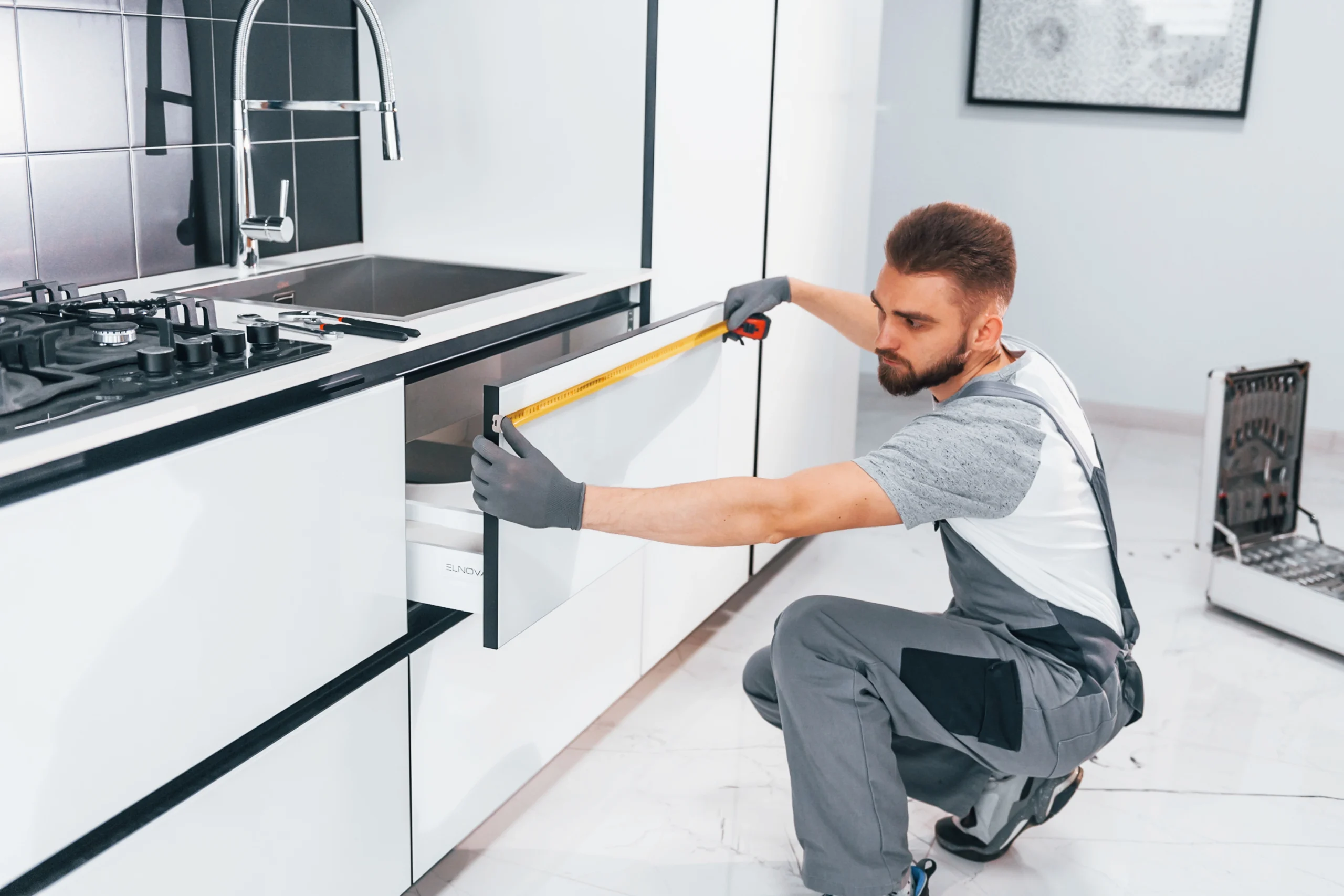 young professional plumber grey uniform measuring table by using meter kitchen scaled Keuken