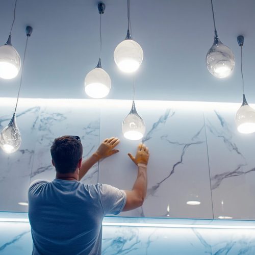 Monteur hangt sierverlichting aan plafond