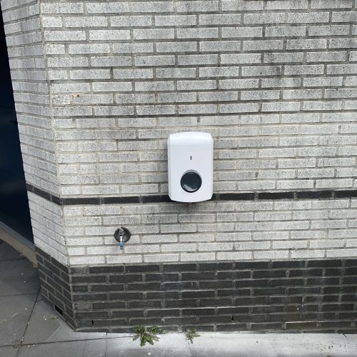 Een witte laad paal die is gemonteerd tegen een grijze muur